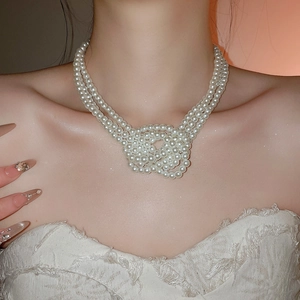 Close-up of French style triple-layered knotted faux pearl necklace on model neck
