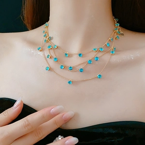 Gros plan sur un collier doré multicouche avec pierres de zircon bleu sur mannequin