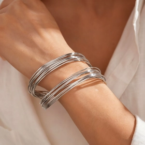Detail shot of a silver layered geometric twisted cuff bracelet worn by a model