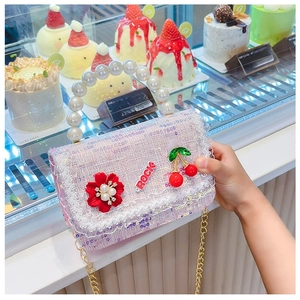 Détail du sac enfant en tweed rose avec poignée en perles et breloques à fleurs