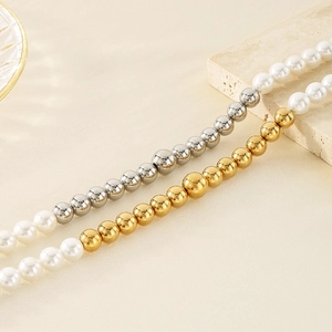 Dettaglio collana di perle bianche con sfere dorate su sfondo in pietra in stile lusso