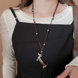 Silver dachshund puppy pendant on brown wax cord necklace worn over a black dress