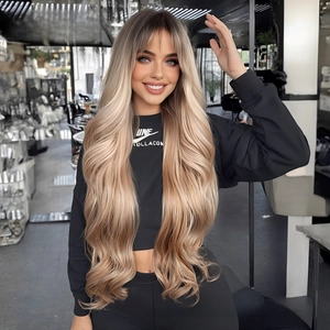 Close-up of long wavy ombre blonde wig with airy bangs on a model in a salon setting