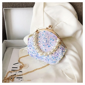 Macro shot of shimmering sequins, pearl handle, and vintage gold clasp on shell bag