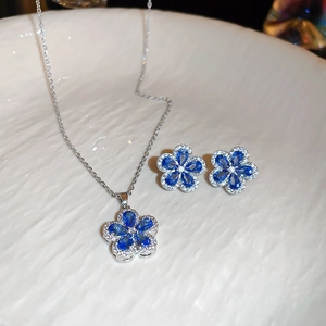 Close-up of blue zircon flower jewelry set with silver necklace and floral stud earrings