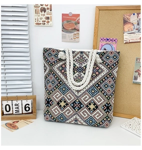 Detail of colorful geometric embroidery and thick twisted rope handles on canvas tote bag