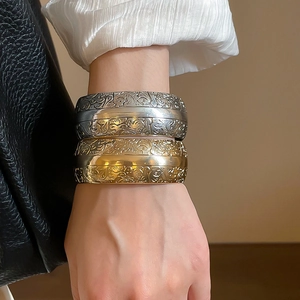 Gros plan détaillé des motifs floraux embossés sur les bracelets larges en métal vintage
