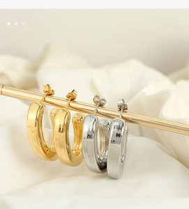 Close-up of polished C-shaped chunky hoop earrings in gold and silver finish