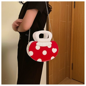 Detailed view of red and white mushroom-shaped handbag with golden chain strap
