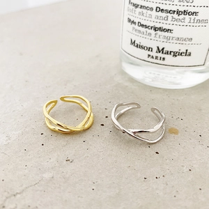 Detailed close-up of minimalist irregular cross rings in gold and silver finishes