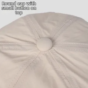 Detail shot of a beige nylon baseball cap showing the top button and six-panel stitching