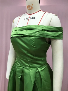 Détails de la robe de soirée en satin vert avec décolleté plissé et texture soyeuse