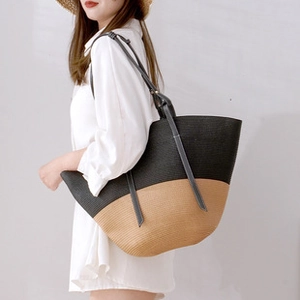 Detail of a two-tone woven straw tote bag featuring black and natural beige contrast