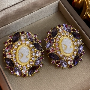 Detail of vintage portrait stud earrings featuring purple marquise rhinestones in a box