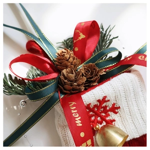 Close-up of Christmas stocking with pine cones, golden bell, and red ribbon bow