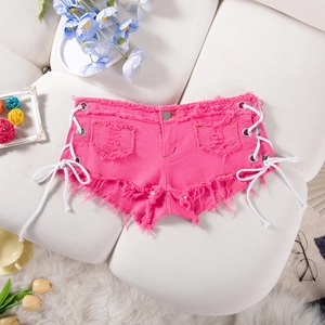 Dettaglio di pantaloncini in denim rosa con lacci laterali e bordi sfrangiati su divano bianco