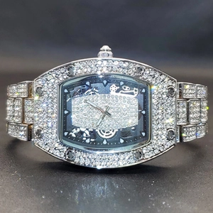 Macro shot of silver iced-out tonneau watch with crystal pavé and hollow dial detail