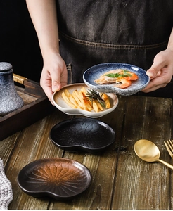 Detail of hand holding a textured ceramic sauce dish with scallop edge and radial pattern