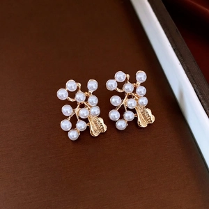 Vintage gold leaf branch earrings set with multiple pearls on a dark textured background