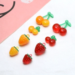 Macro detail of glossy resin strawberry and cherry charms for DIY handmade jewelry crafts