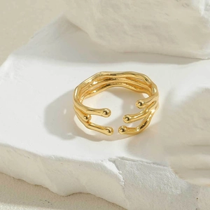 Macro shot of an irregular gold-finished metal ring on a textured stone surface