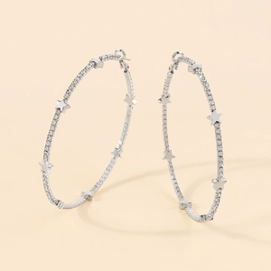 Dettaglio di grandi orecchini a cerchio argento con stelle brillanti e strass incastonati