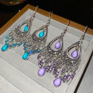 Bohemian geometric teardrop tassel earrings with blue and purple stones on velvet tray