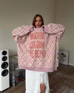 Close-up of pink and orange oversized knit sweater with floral patterns and Russian text