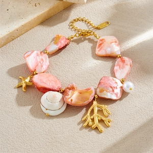 Bohemian gold starfish and shell bracelet with pink beads on stone background