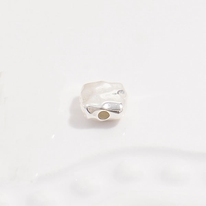 Macro view of vintage irregular S925 silver square bead with hammered texture and hole