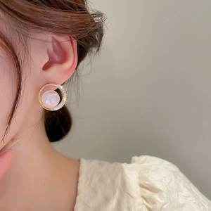 Macro view of gold plated hoop earring with zircon inlay and iridescent pearl center