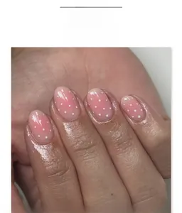 Detailed view of pink gradient press-on nails with white polka dots in oval shape