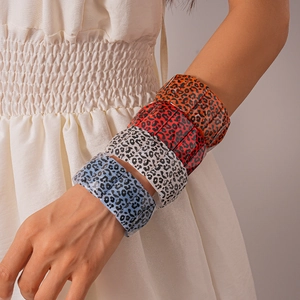 Detail of four acrylic leopard print bangles in orange, red, beige and blue tones