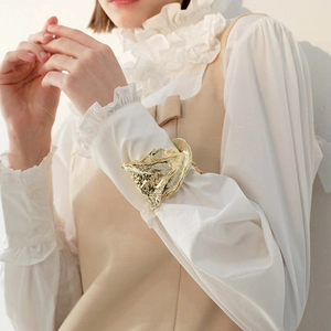 Detailed close-up of a chunky gold irregular textured metal cuff on a woman's wrist