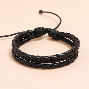 Détail d'un bracelet en cuir tressé noir multicouche avec fermeture à cordon réglable