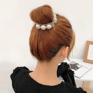 Elegant gold metal hair claw clip with large faux pearls shown in a hair bun on a woman