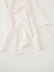 Detailed close-up of flowing white chiffon hem with elegant ruffle and neat stitching
