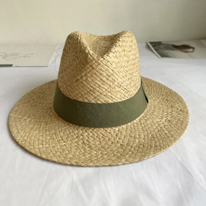 Detail of hand-woven natural raffia straw Panama hat with elegant dark green silk ribbon
