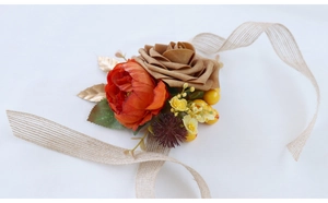 Detail of vintage wedding corsage with orange and khaki flowers and linen ribbon