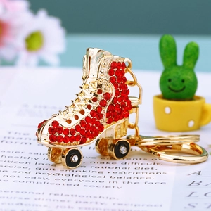 Close-up of golden ice skate keychain with red rhinestones on a decorative paper background