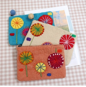 Detail of three handmade wool felt coin purses with colorful flower embroidery and zipper