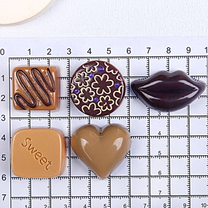 Detailed view of assorted resin chocolate charms on a centimeter measurement grid