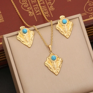 Irregular gold necklace and earrings set with blue turquoise in a beige jewelry box