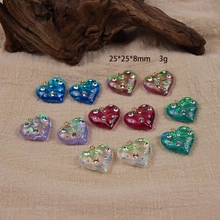 Flat lay of colorful resin heart charms with glitter on natural burlap and wood background
