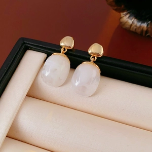Detail view of 18K gold plated resin earrings displayed inside a premium black jewelry box