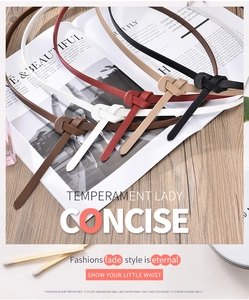 Flat lay of slim leather belts in five colors on a wooden table with magazines