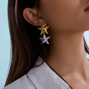 Two-tone 18K gold and silver stainless steel star drop earrings on female model