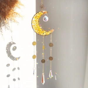 Detailed view of crescent moon crystal suncatcher reflecting rainbow light on a white wall