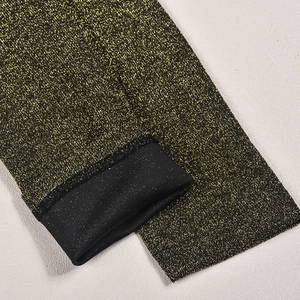 Dettaglio macro del tessuto glitterato dorato con fodera elastica in maglia nera
