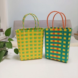 Detail view of two hand-woven straw bucket bags in yellow and green color blocking
